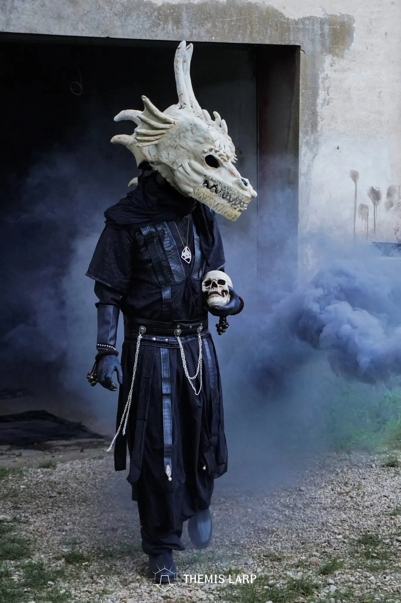 Personaggio di Themis con una grande maschera draconica, avvolto dal fumo
