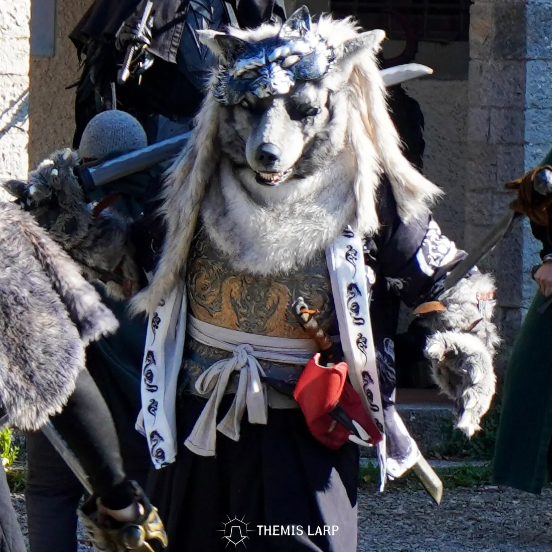 Personaggio di Themis con maschera da lupo e costume ispirato a una creatura fantastica